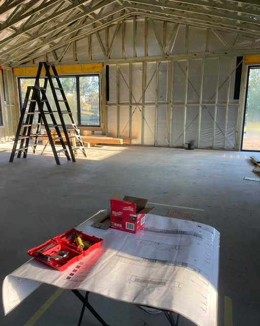 House under construction with electrical plans spread out on a trestle table